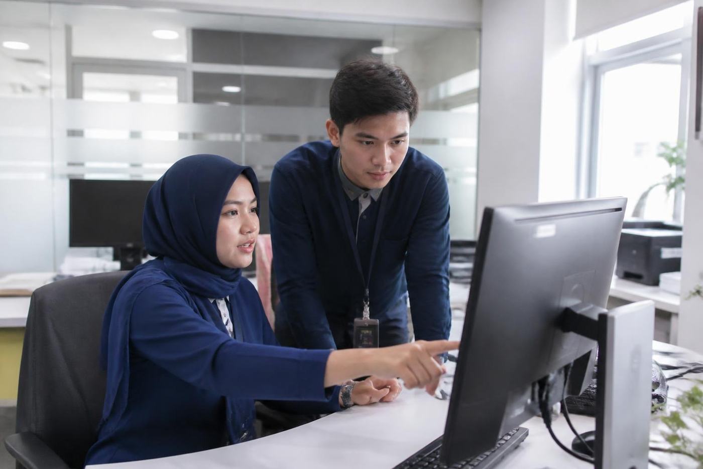 Two hospital coding staff review a patient document on a monitor